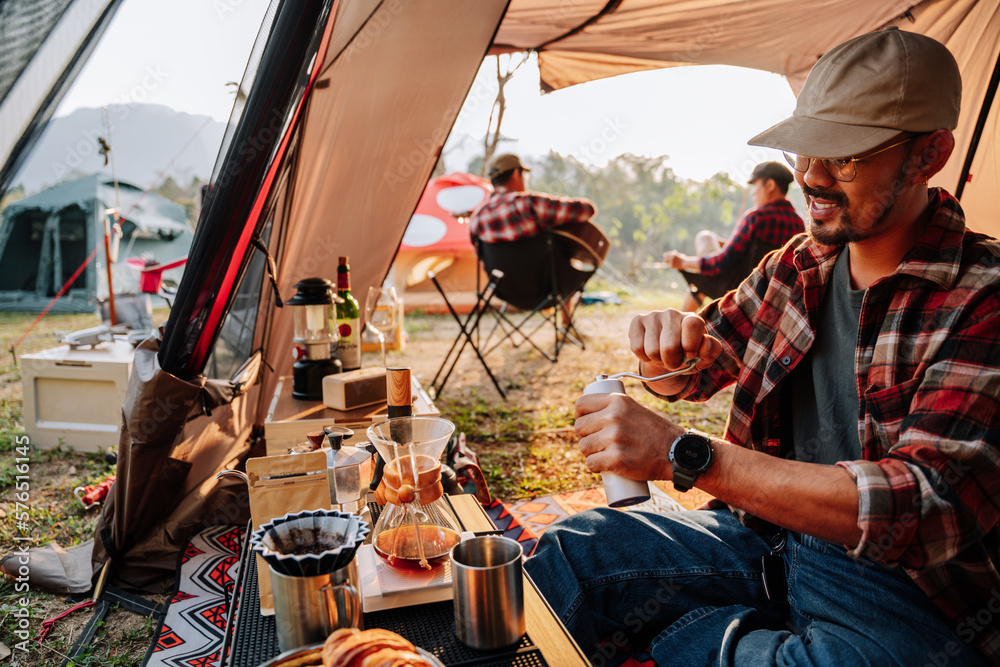 Camping with friends and drip coffee in the camp man using manual coffee grinder Coffee drip and cam