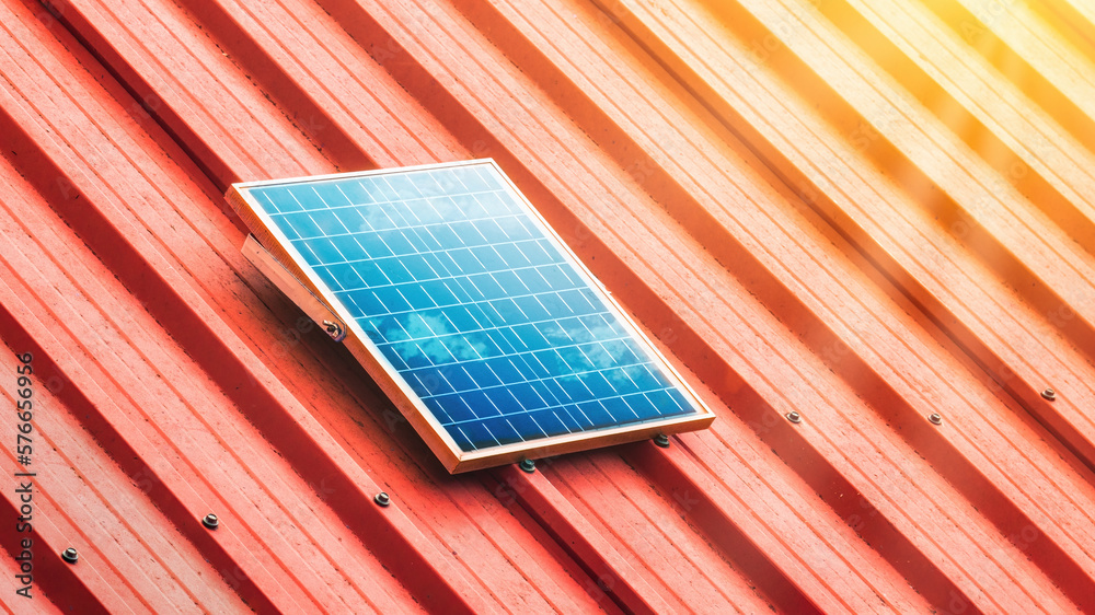 Small solar panel installed on red metal roof with sun shine in summer.