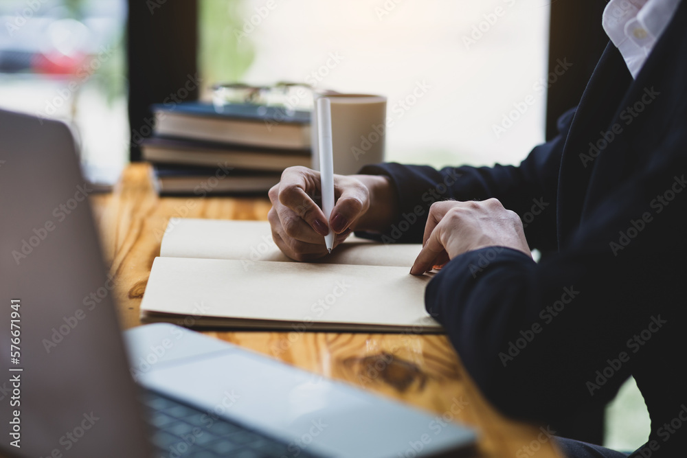 Businesswoman in office working with laptop and writing work schedule.