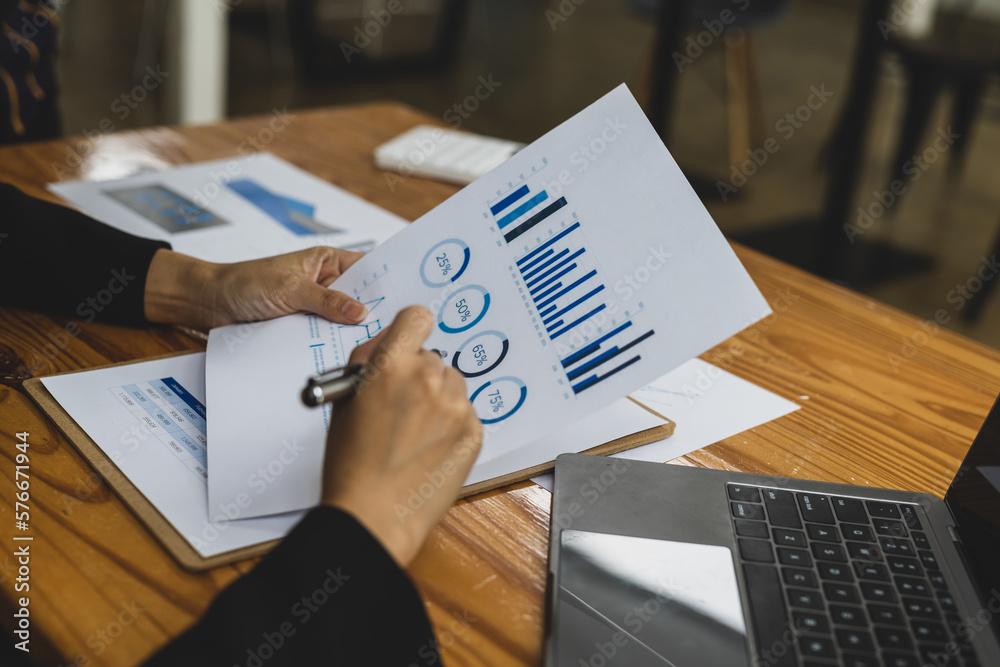 Businesswoman working with financial documents analyzing market growth report and company sales.