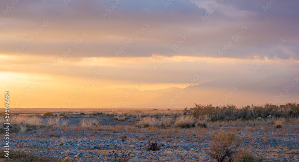 Colorful sunset with sun rays through misty clouds. Mountains in the cloudy sky. Atmospheric mountai