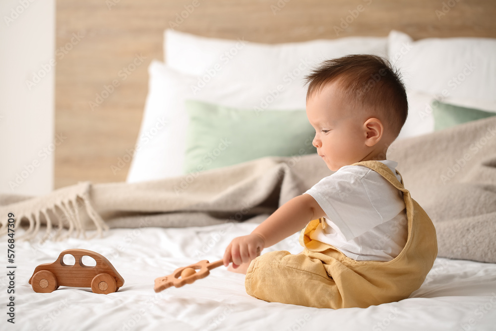 Baby boy playing with rattle in bedroom