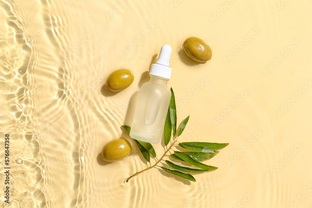 Bottle of essential olive oil in water on color background