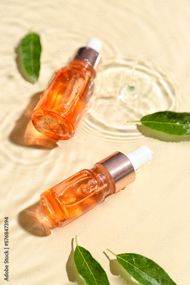 Bottles of essential olive oil and plant leaves in water on color background