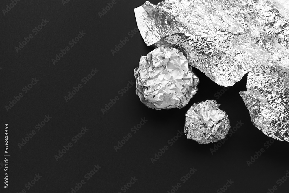 Crumpled balls of aluminium foil on dark background