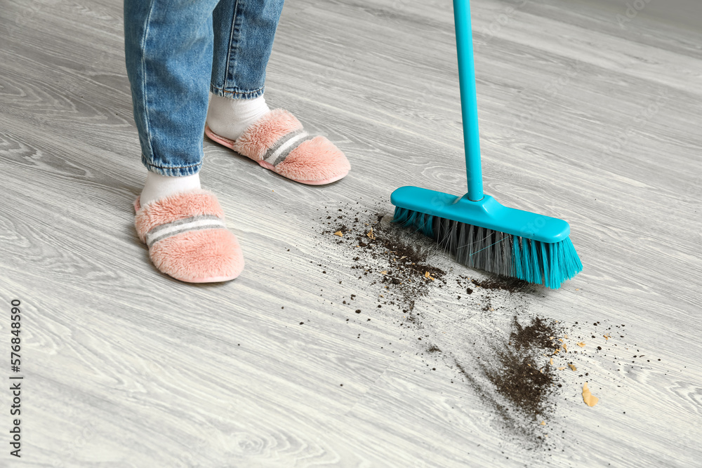 Woman sweeping floor with broom