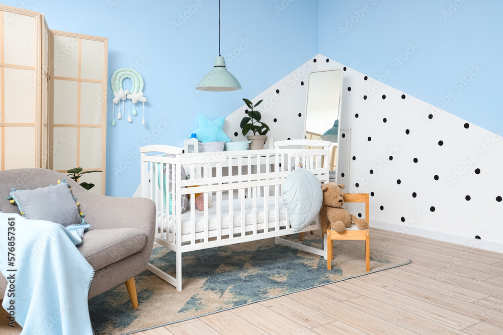 Interior of childrens bedroom with crib, armchair and mirror