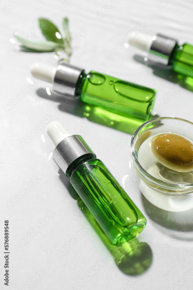 Bottles of essential olive oil in water on white background, closeup