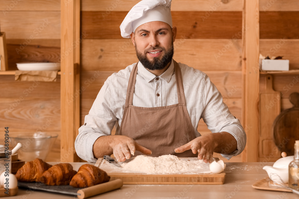 Male baker making dough at table in kitchen