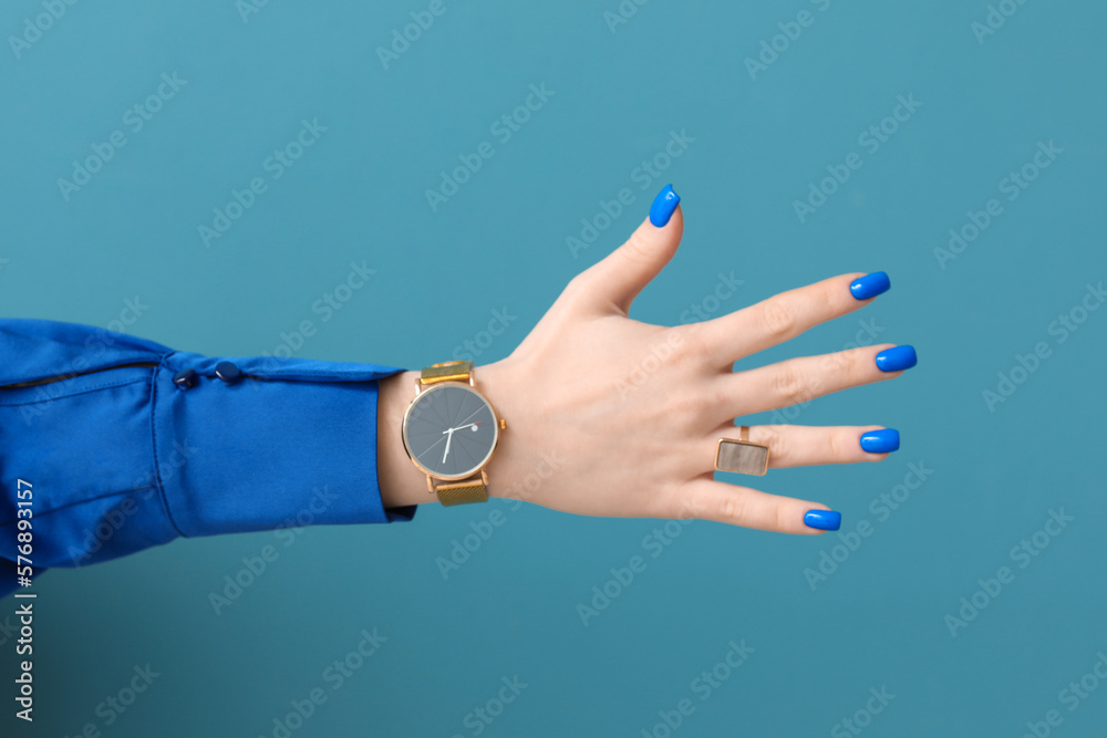 Woman with golden wristwatch on blue background