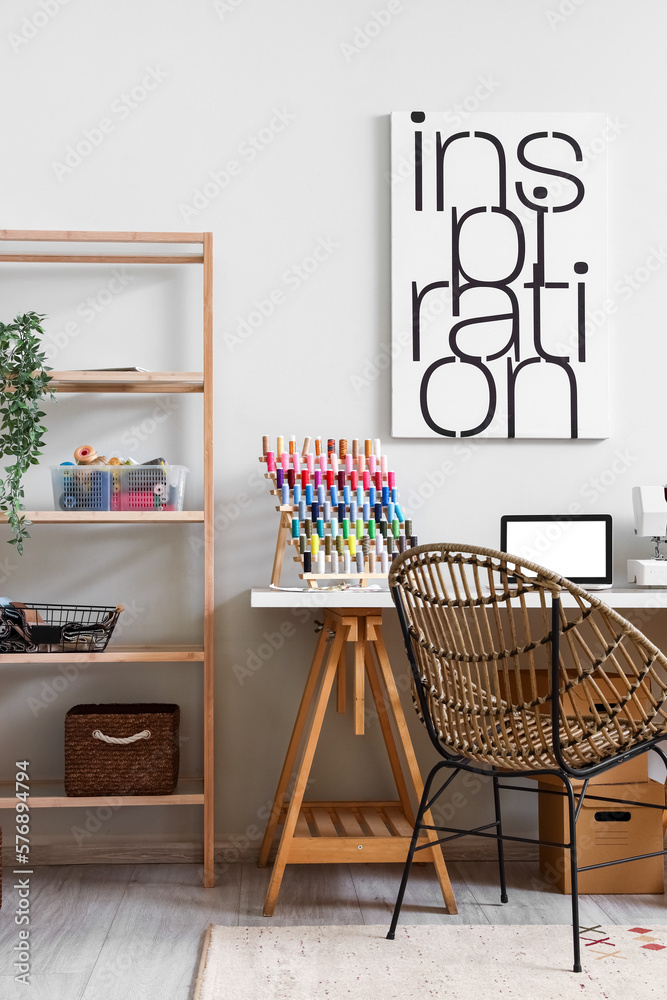 Interior of modern atelier with tailors workplace and shelving unit