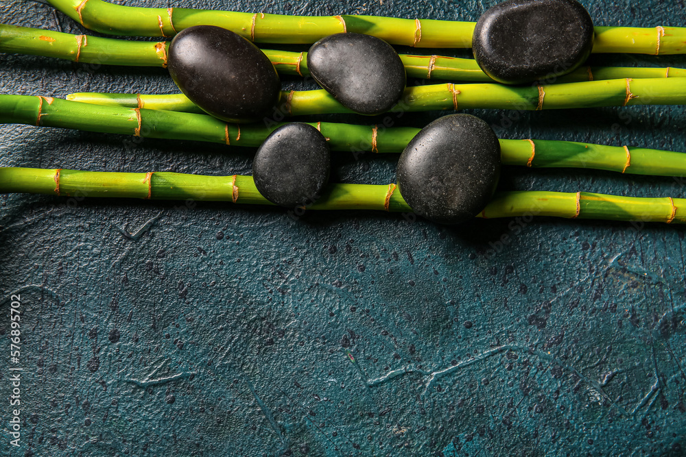 Spa stones and bamboo on dark background, top view