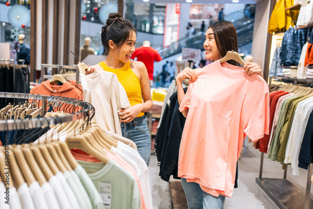 Asian two beautiful women looking at clothes product in shopping mall. 