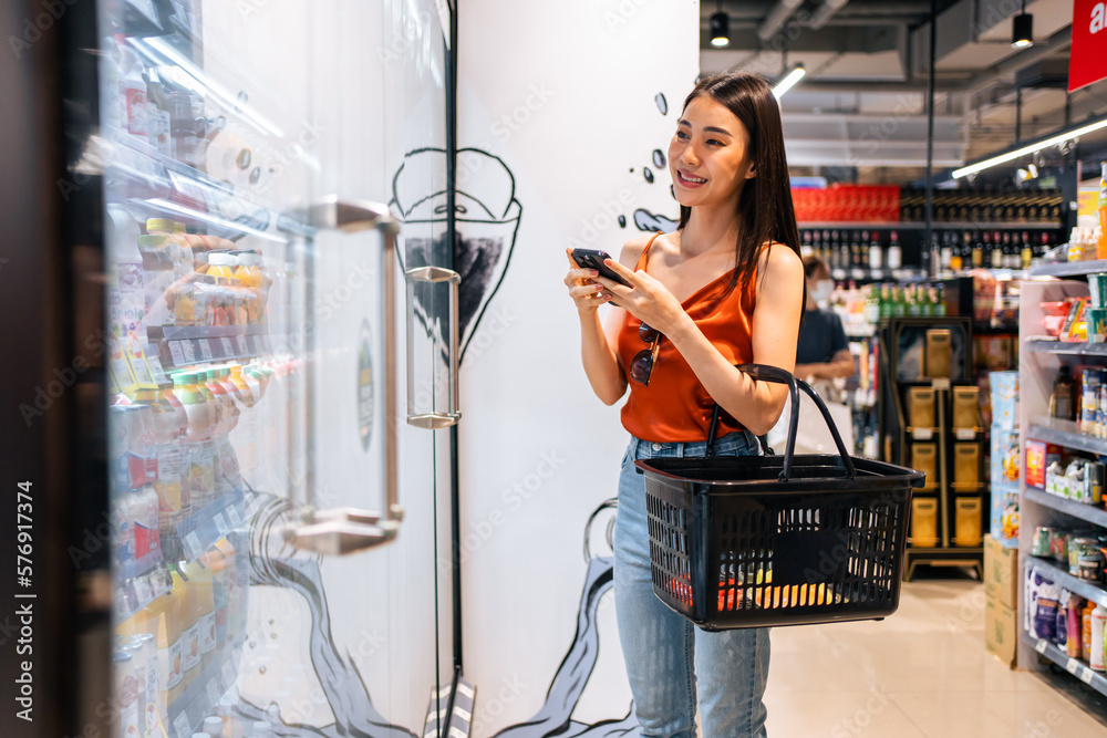 Asian young beautiful woman holding grocery basket walk in supermarket. 