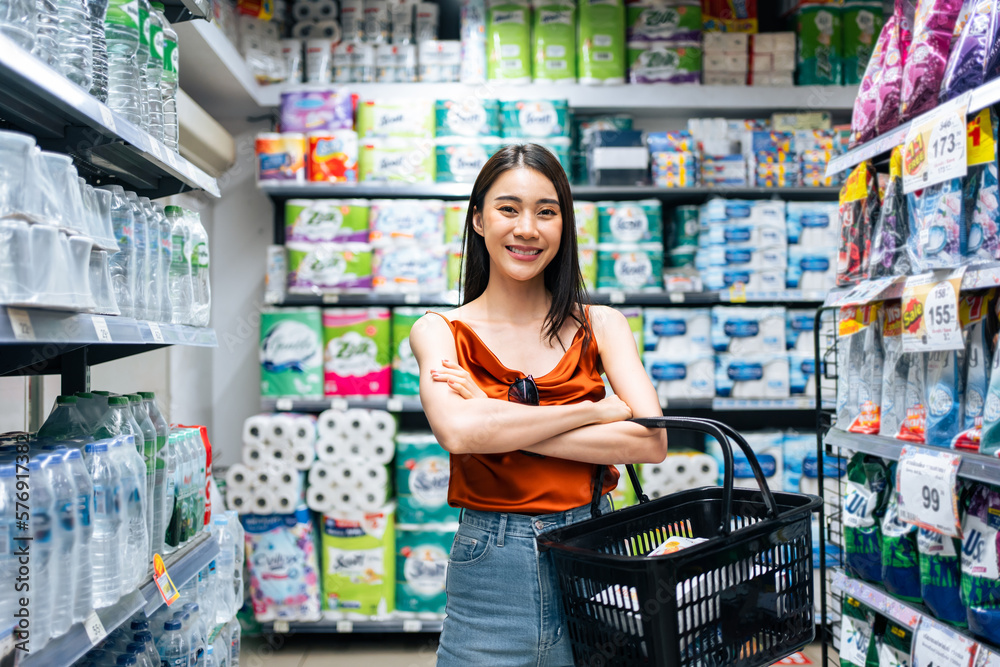 Portrait of Asian young woman hold grocery basket walk in supermarket. 