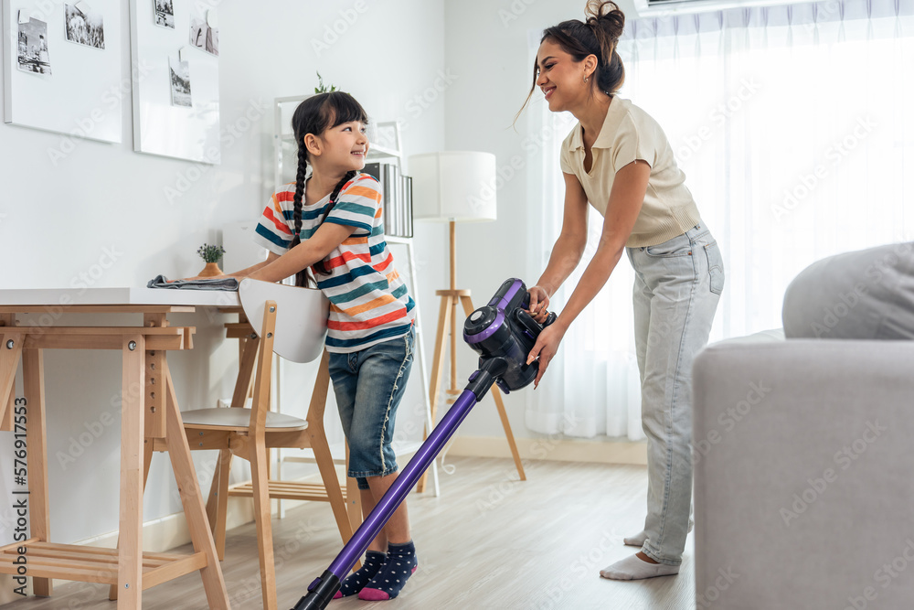 Caucasian beautiful mother cleaning house with young kid daughter. 