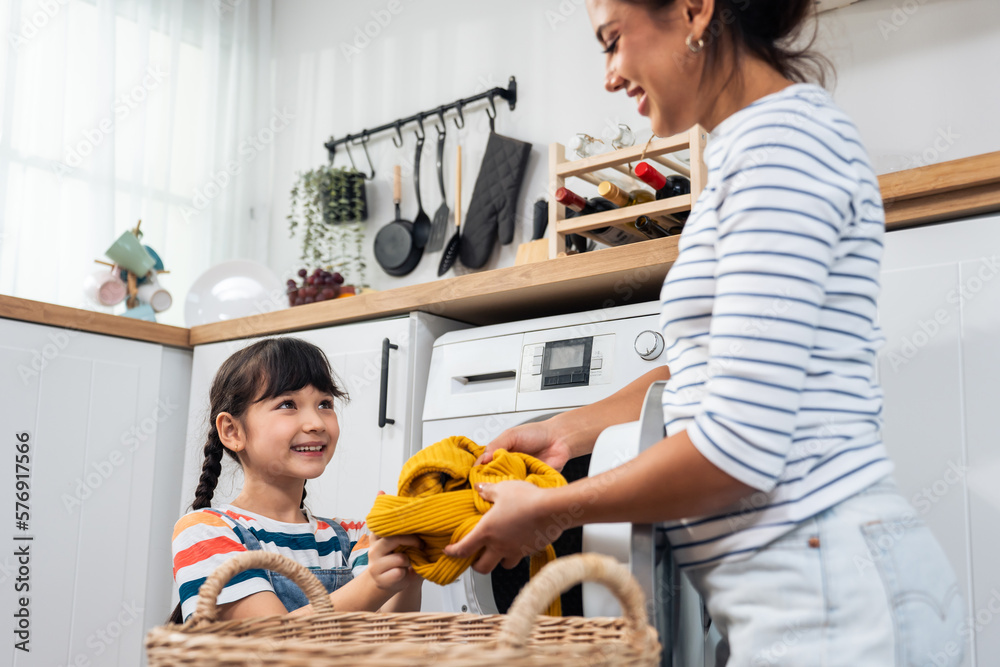 Caucasian beautiful mother teaching young daughter wash dirty clothes. 