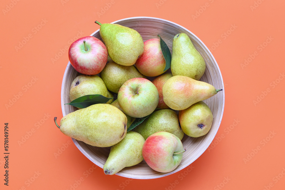 Bowl of fresh pears and apples on color background