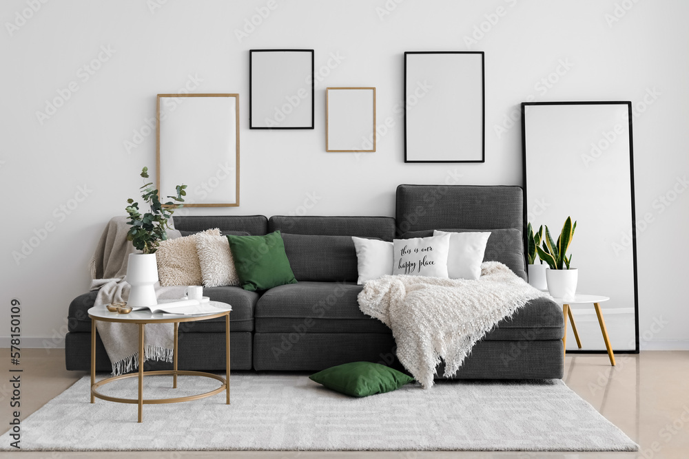 Interior of living room with black sofa, tables and blank frames