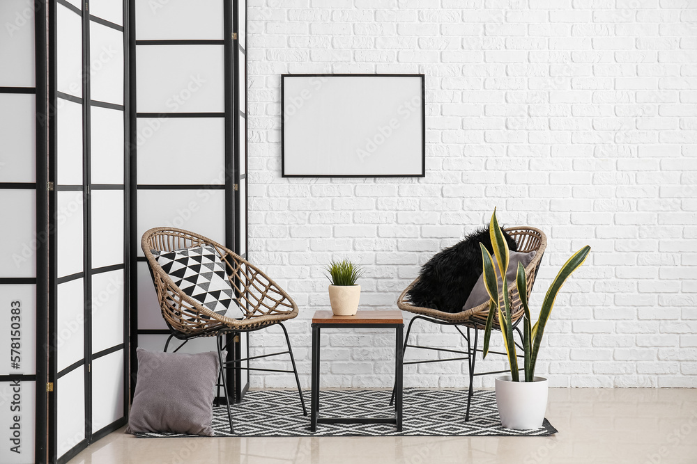 Interior of cozy living room with folding screen, chairs and table