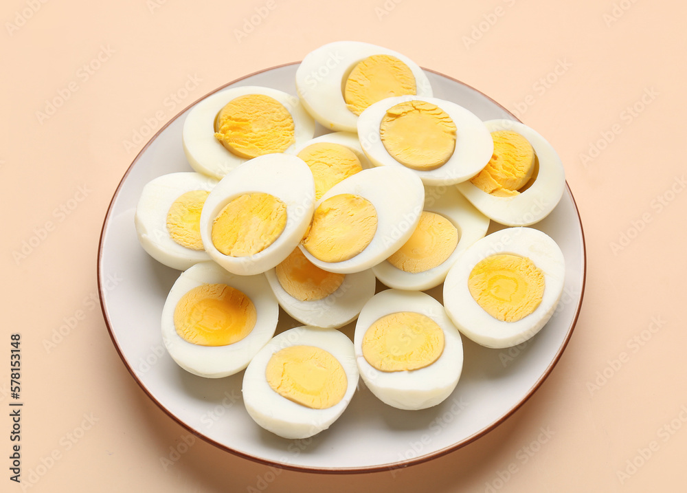 Plate with halves of delicious boiled eggs on beige background