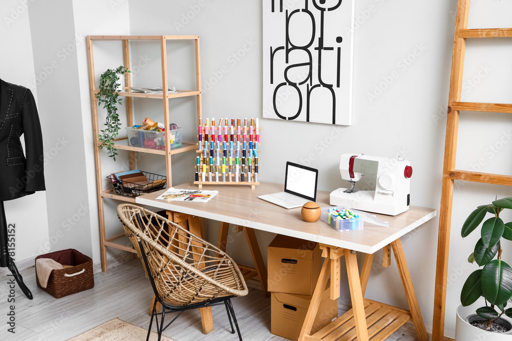 Interior of modern atelier with tailors workplace and shelving unit