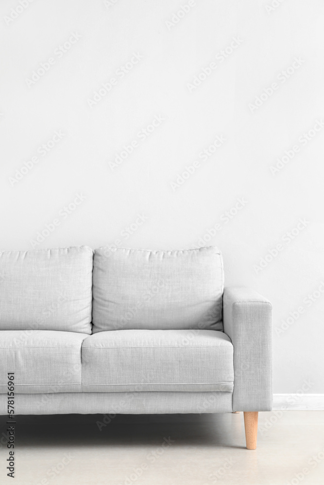 Stylish grey sofa near white wall