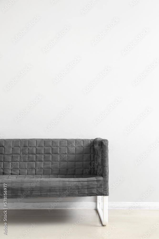 Stylish grey sofa near white wall