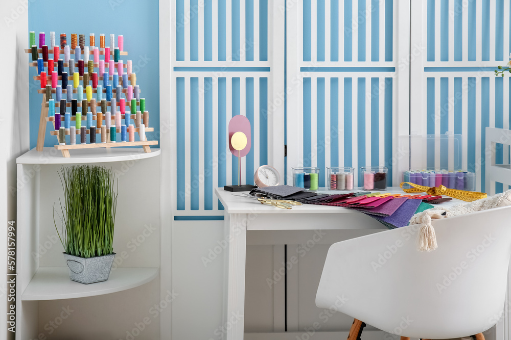 Interior of atelier with tailors workplace, thread spools and shelving unit