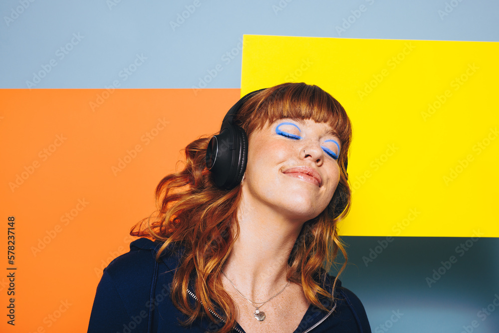 Carefree woman listening to relaxing music with geometric shapes in the background