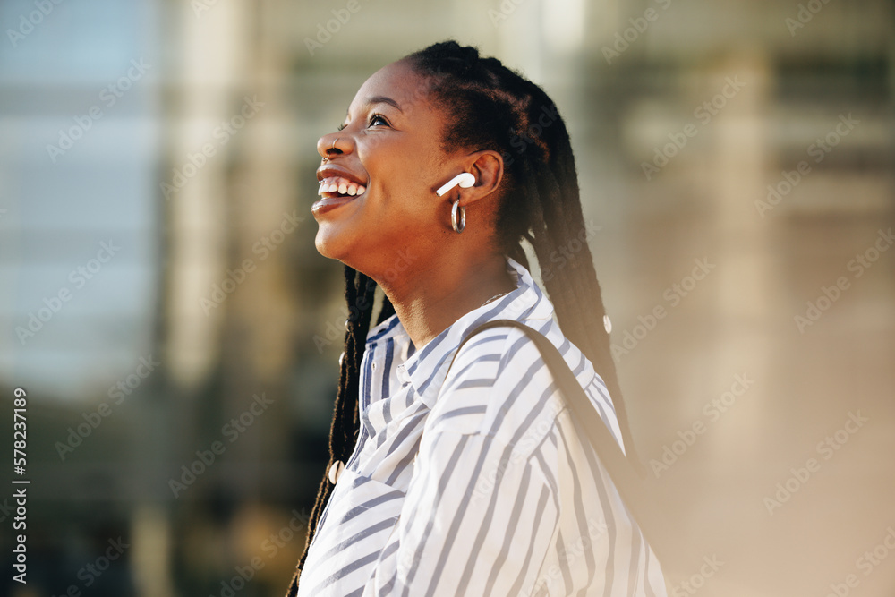 Sideview of a cheerful young businesswoman listening to music on her way to work in the city