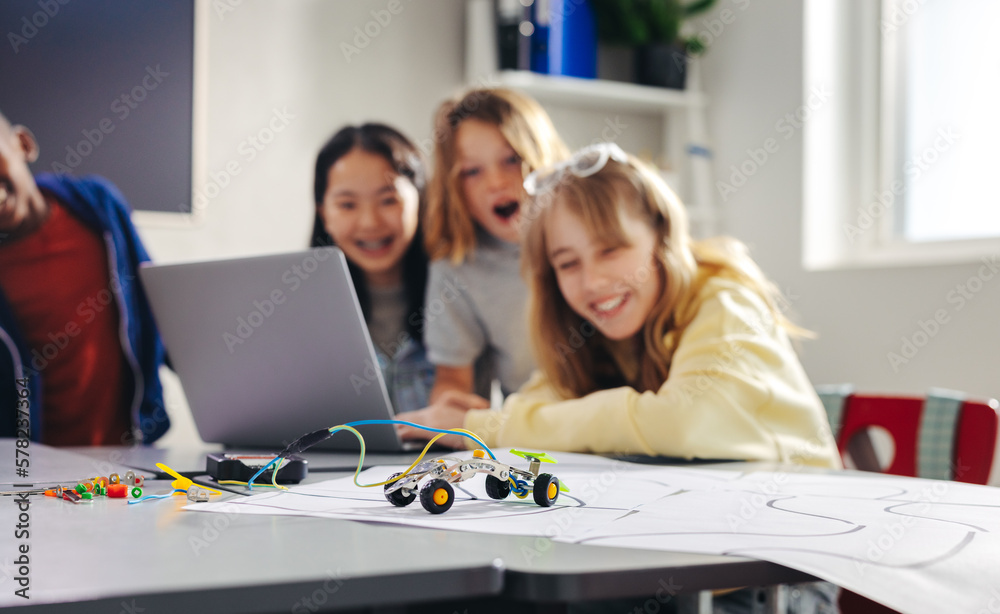 Practical lesson in robot programming: Kids use a computer code to control a robot car