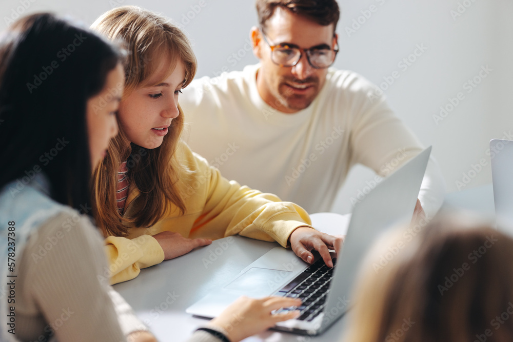 Digital literacy for young minds: Male tutor guiding young children in a computer class