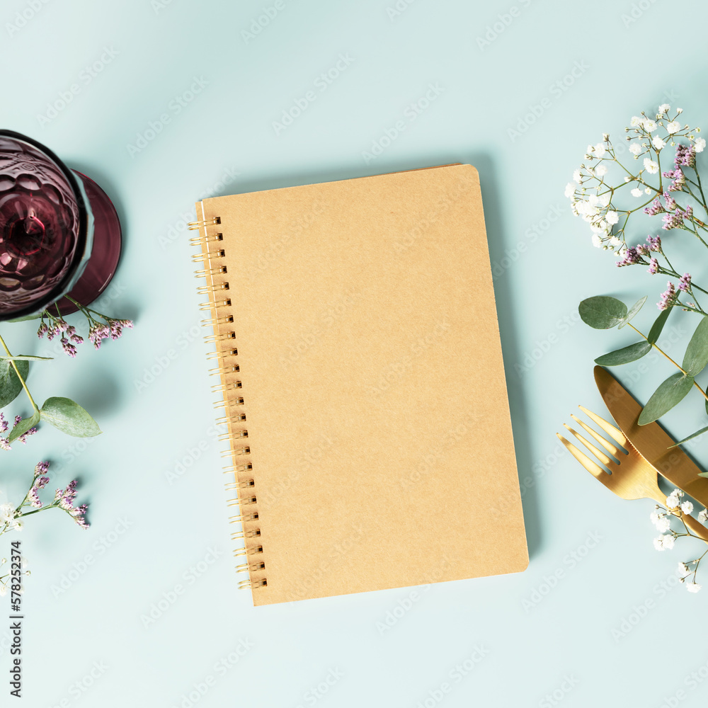 Notebook and table decorations on blue background. Flat lay top view copy space mockup