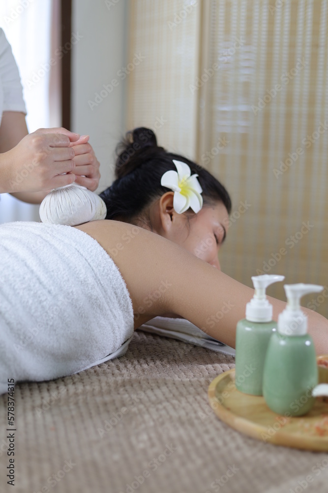 Woman Enjoying Herbal Massage. Relaxed Asian girl sleeping with eyes closed receiving traditional Th