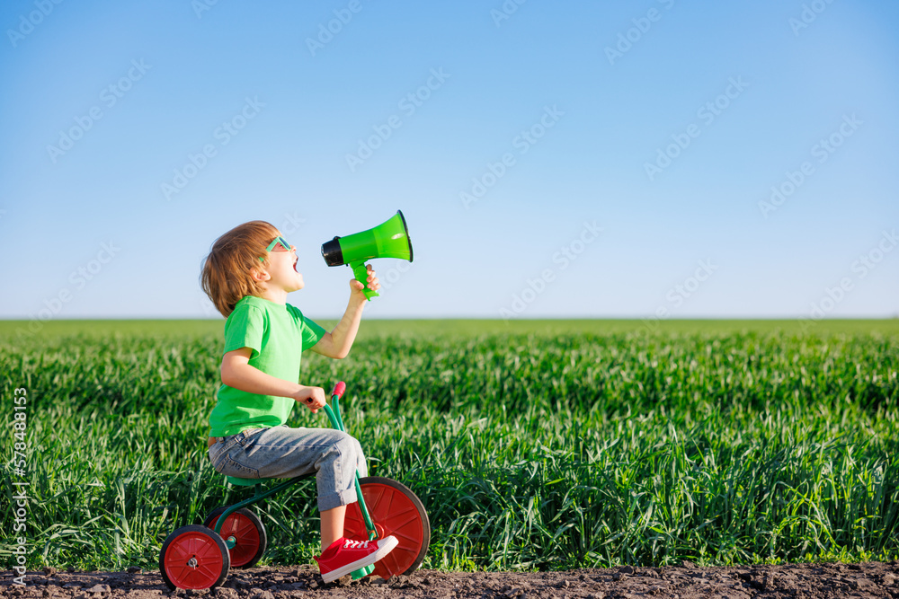 Child shouting through loudspeaker against blue summer sky