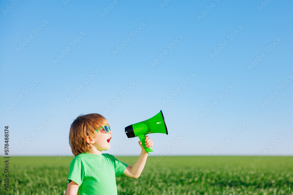 Happy child shouting through loudspeaker against blue summer sky