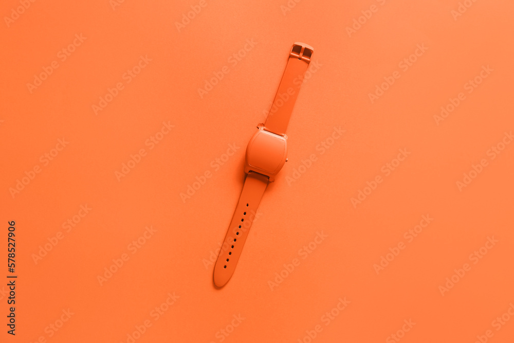 Orange wristwatch on color background