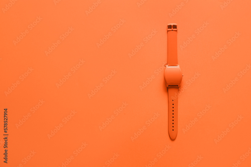 Orange wristwatch on color background