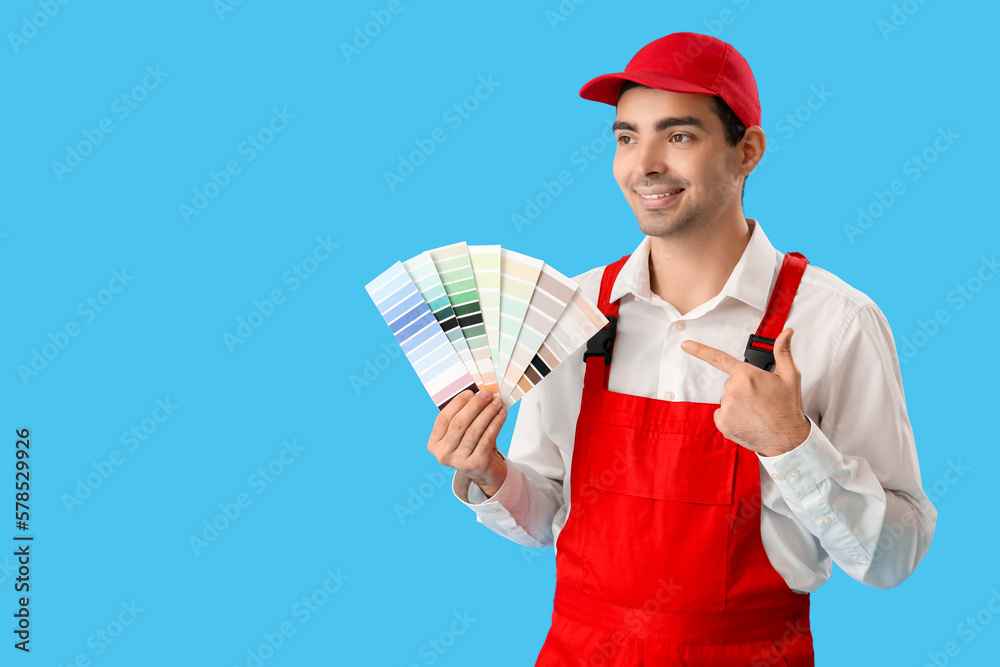 Male painter pointing at color palettes on blue background