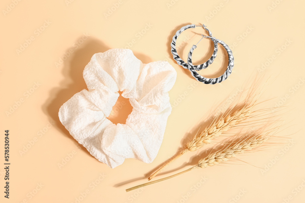 Stylish scrunchy, earrings and wheat spickelets on color background