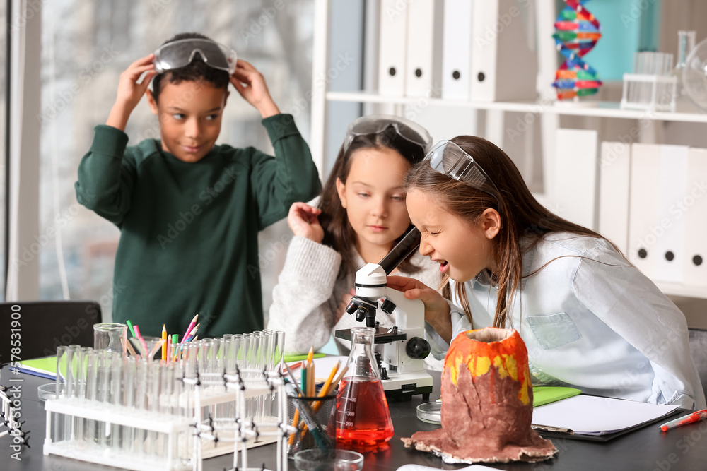 Cute little children with microscope in science classroom