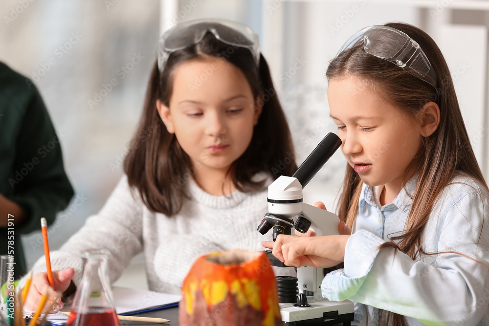 Cute little children with microscope in science classroom