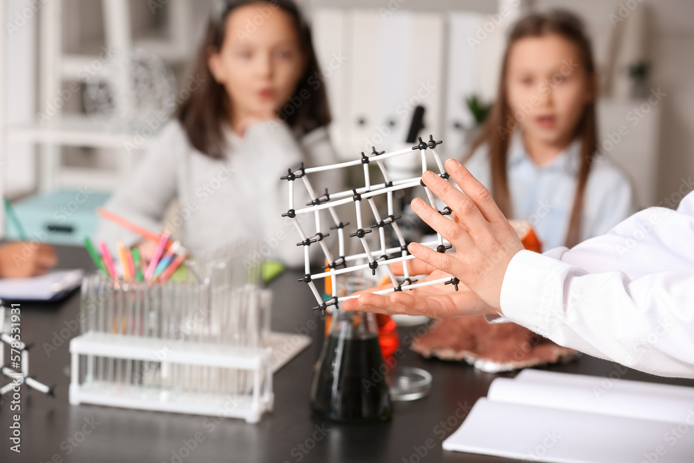 Teacher with molecular model conducting lesson to little children in science classroom, closeup