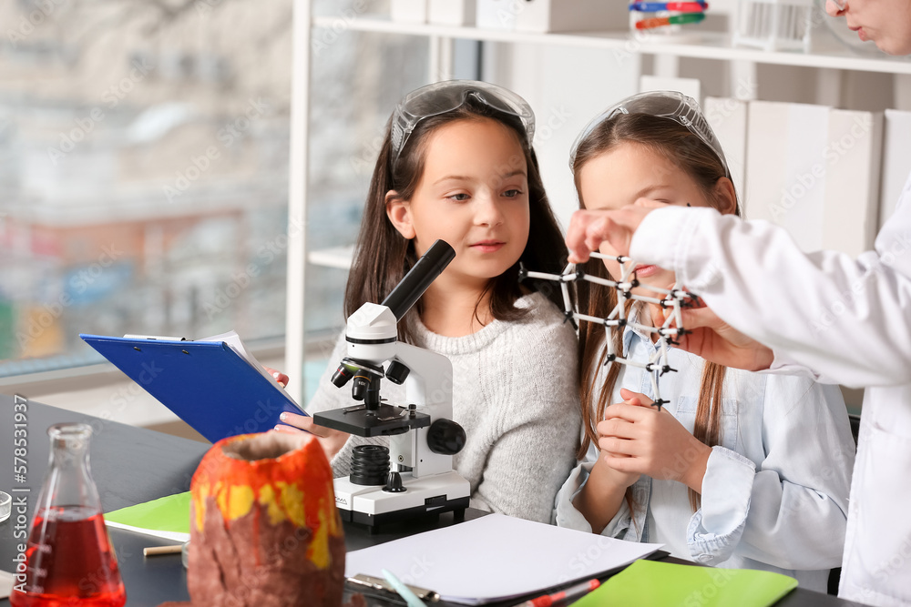 Chemistry teacher with molecular model conducting lesson to little girls in science classroom