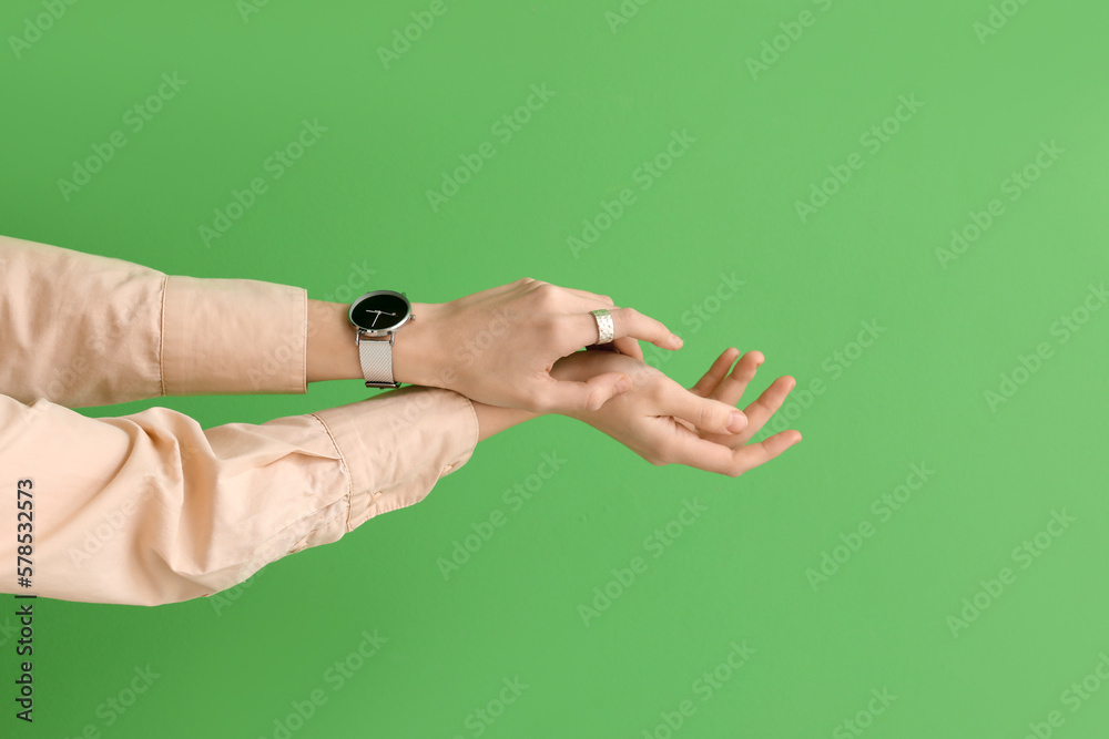 Woman with stylish wristwatch on green background