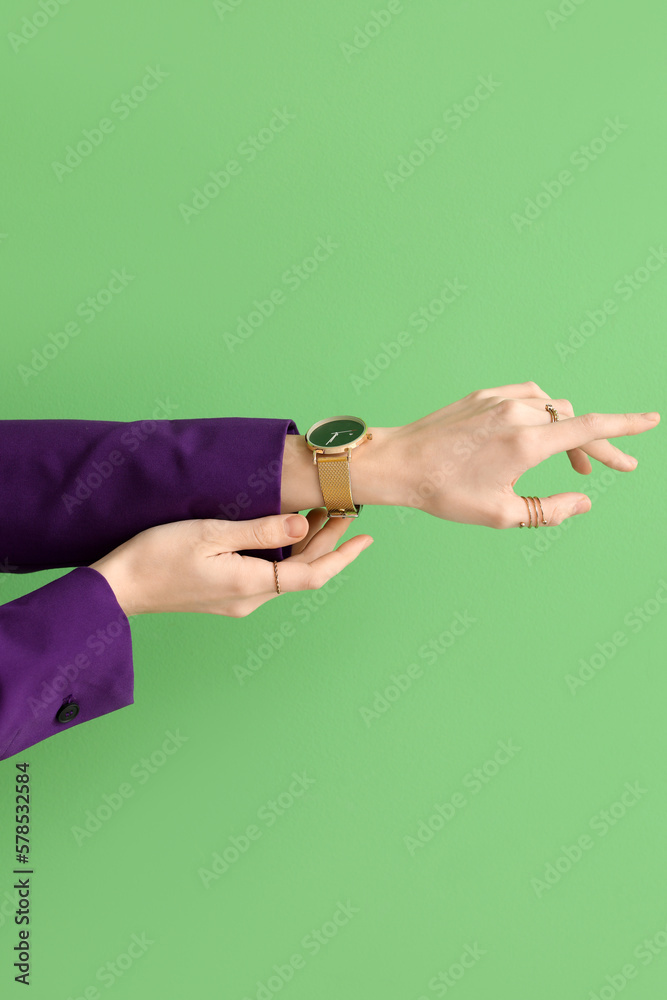 Woman with golden wristwatch on green background