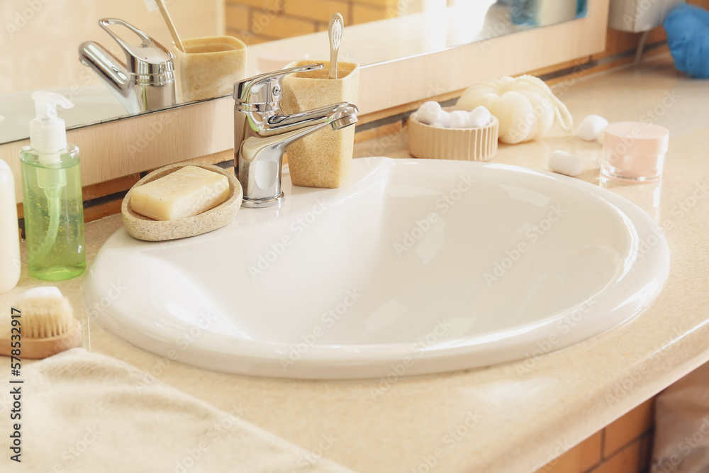 Table with white ceramic sink and bath supplies in room