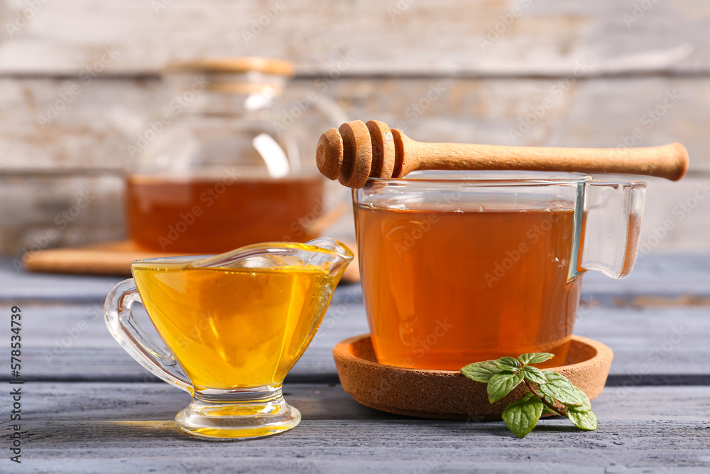 Cup of green tea and gravy boat with honey on color wooden table