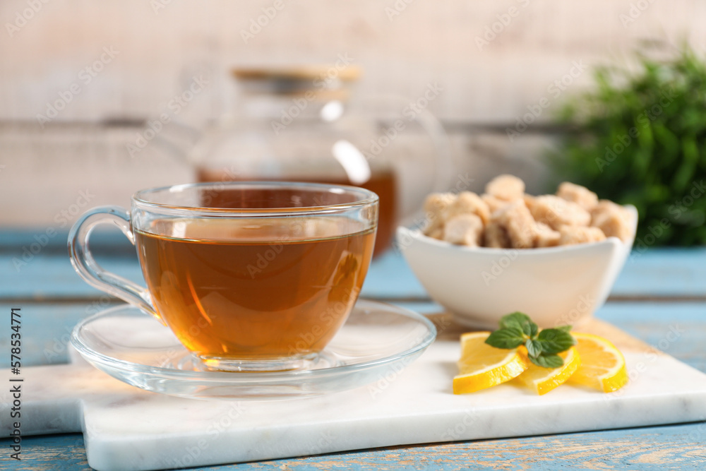 Board with cup of tasty green tea, lemon slices and cane sugar on color wooden table